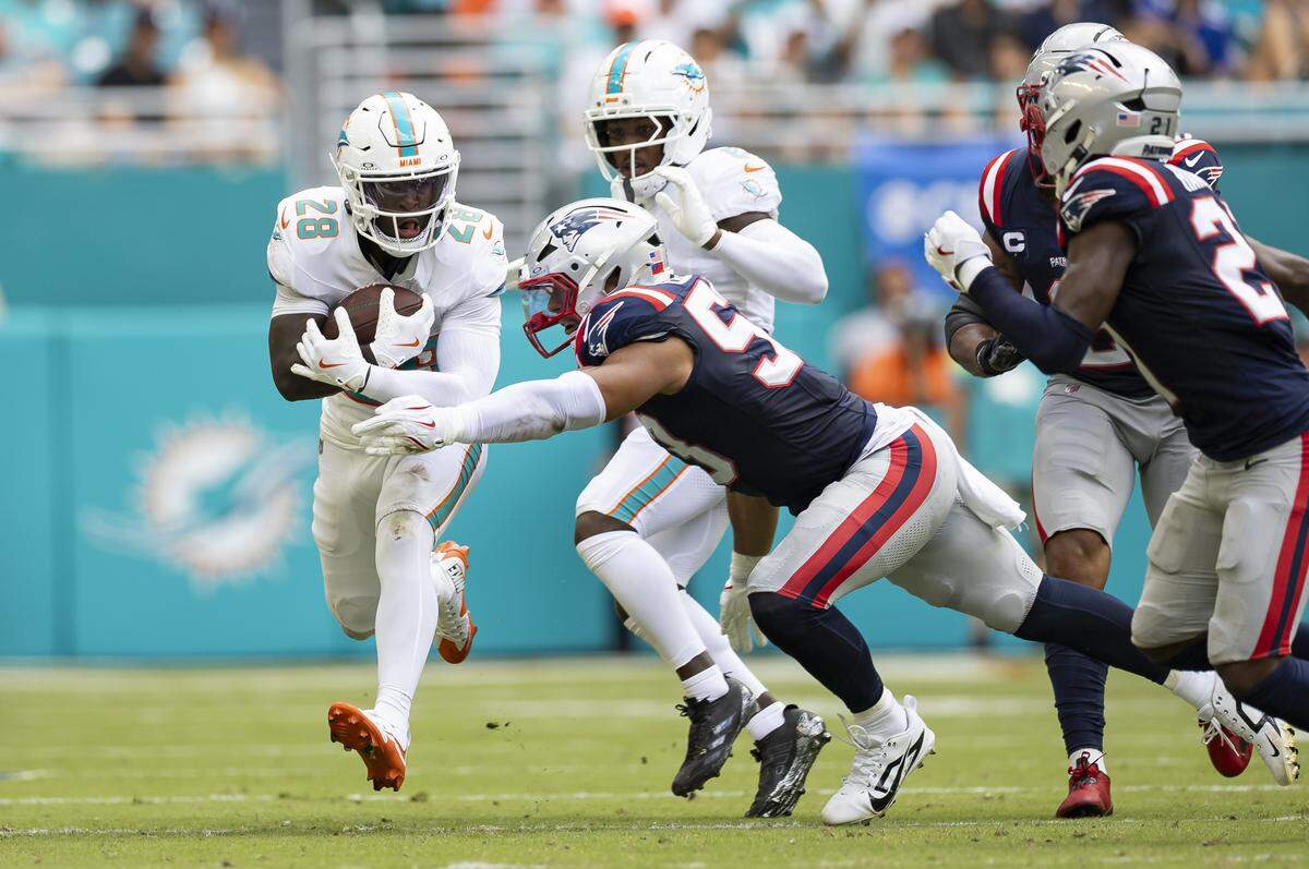 Miami Dolphins running back De'Von Achane (28) runs with the ball as New England Patriots linebacker Christian Elliss (53) tries to stop him in the first half of their NFL game at Hard Rock Stadium on Sunday, Sept. 14, 2025, in Miami Gardens, Fla.