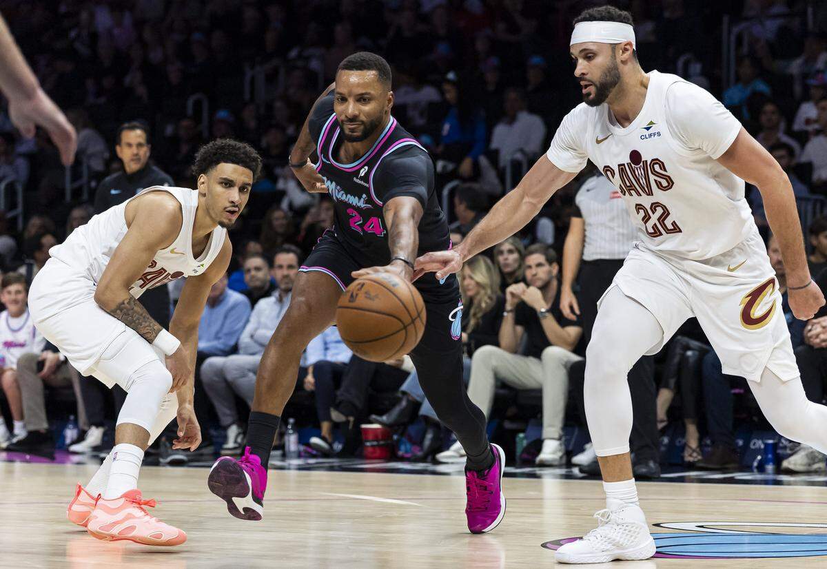 Miami Heat guard Norman Powell (24) competes for the ball against Cleveland Cavaliers forward Larry Nance Jr. (22) and guard Tyrese Proctor (24) in the second half of their NBA game at Kaseya Center on Nov. 12, 2025, in Miami.