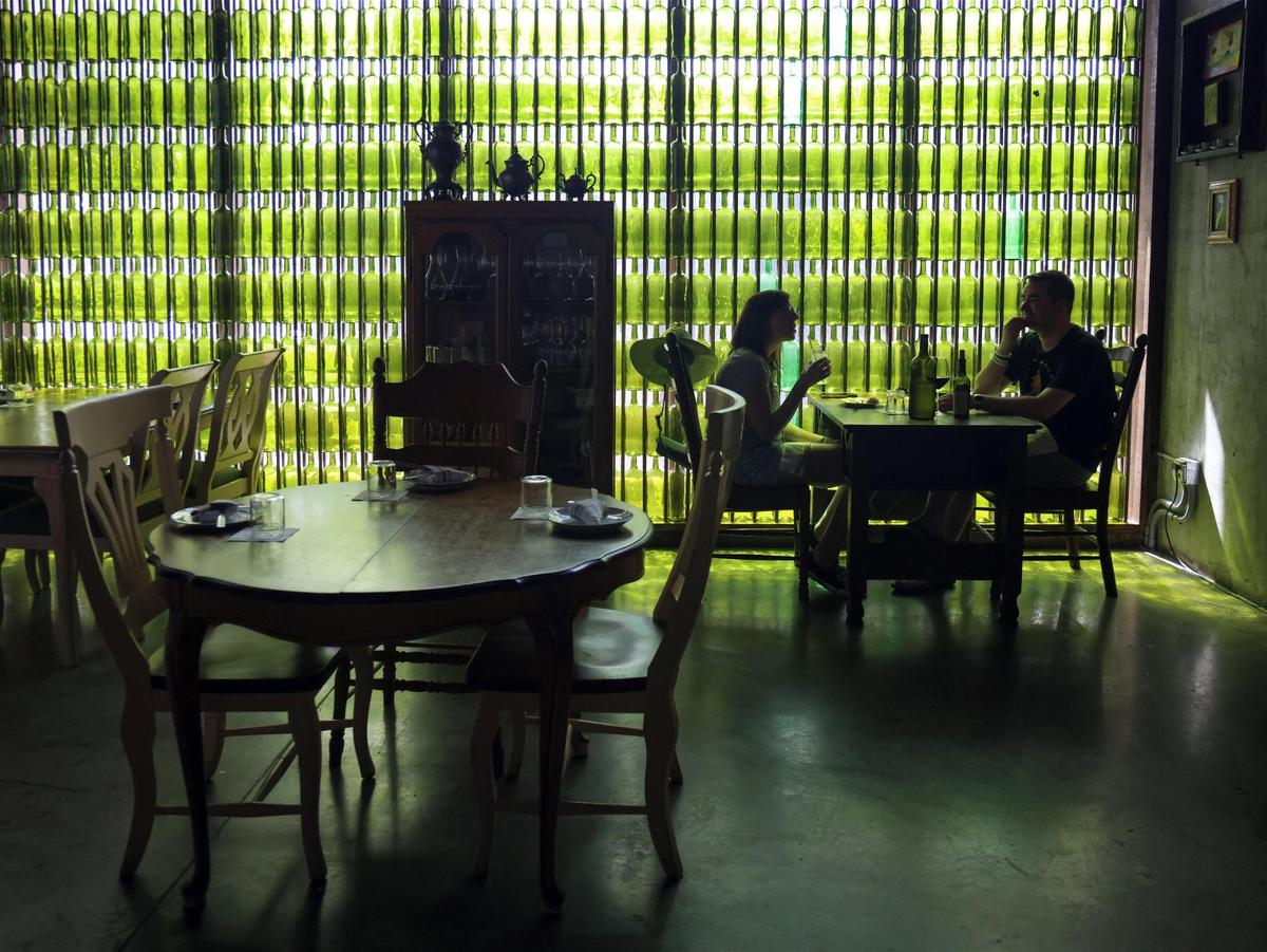 Clientes disfrutan del almuerzo con el telón de fondo de las botellas de vidrio verde coleccionadas por las propietarias en Bunbury.