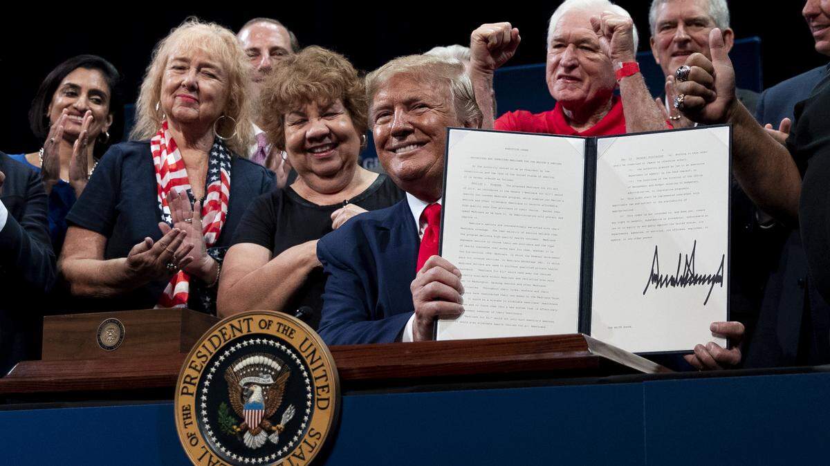 President Donald Trump displays a signed executive order related to Medicare on Thursday, Oct. 3, in The Villages, a large retirement community in Central Florida. Some experts say the measure could lead to seniors paying more for their medical costs.