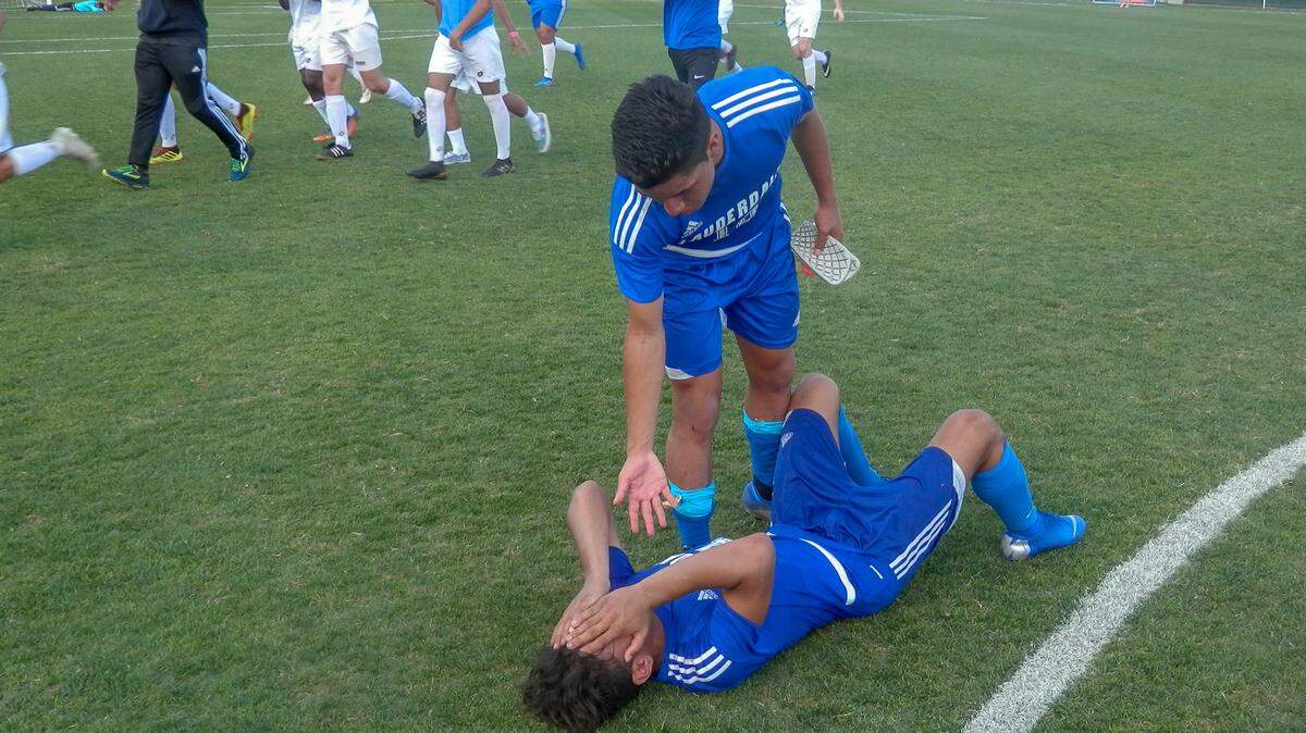 Fort Lauderdale’s Steven Noguera tries to help teammate Camilo Prado up off the ground seconds after the final whistle of the Flying L’s overtime loss to Auburndale in the Class 4A state championship game.