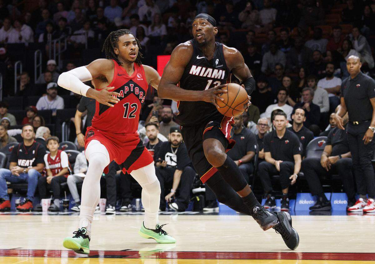 Miami Heat center Bam Adebayo (13) drives the ball passed Toronto Raptors forward Collin Murray-Boyles (12) during the second half of a game on Monday, Dec. 15, 2025, at the Kaseys Center in downtown Miami, Fla. The Heat lost to the Raptors. 