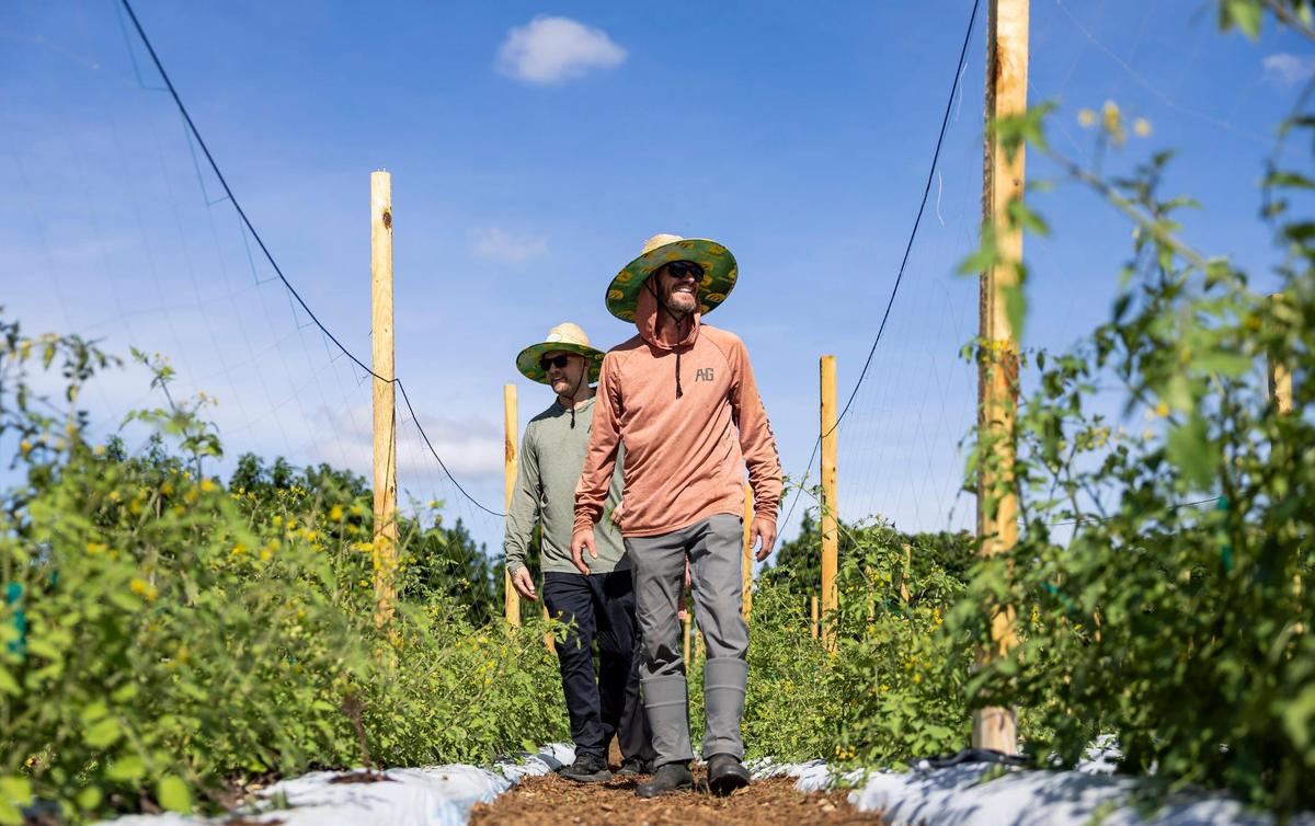 Jeremy Ford, left, and Joe Mizzoni walk through the fields at Ford’s Farm in the Redland.