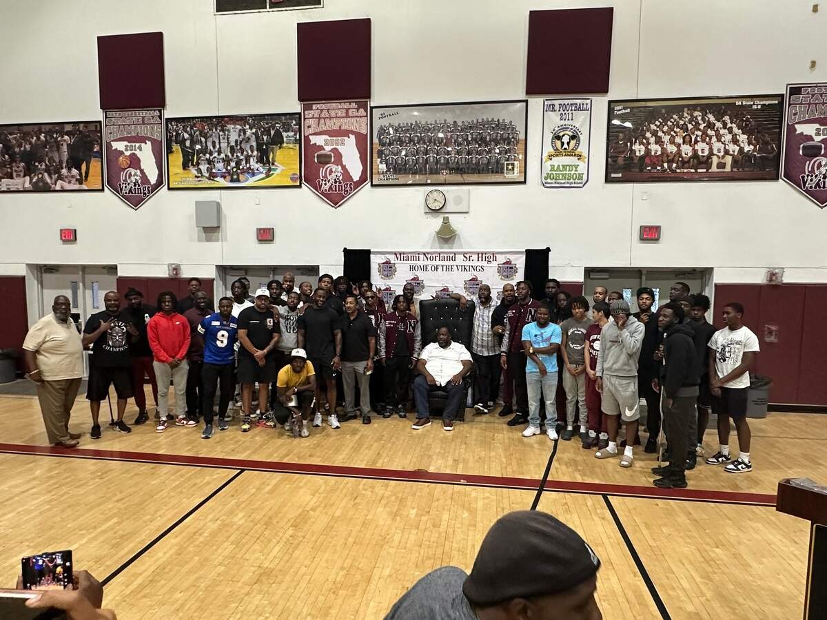 Miami Norland boys’ basketball coach Lawton Williams III (middle) is surrounded by several of his former players who attended a ceremony this past week where the school announced it would rename its gym in his honor.