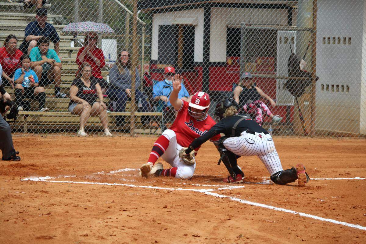 Sara Breaux slides home safe in the first inning with Doral’s first run as Cooper City catcher Kirsten Caravaca tried to apply the tag in the Firebirds’ 5-2 win in the Region 4-6A final on Saturday at Cooper City High.