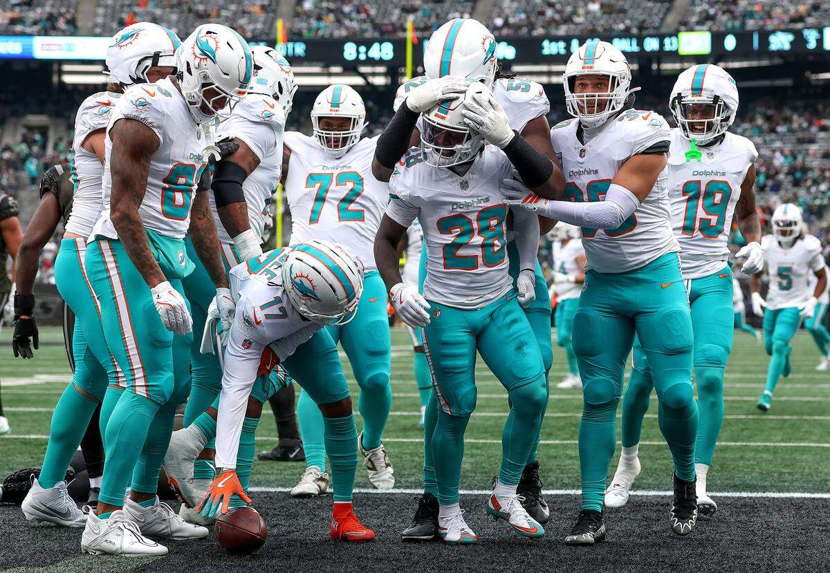 El running back de los Dolphins de Miami De'Von Achane (#28) celebra con sus compañeros de equipo tras anotar un touchdown en el partido contra los Jets, efectuado el 7 de diciembre de 2025 en Nueva York.
