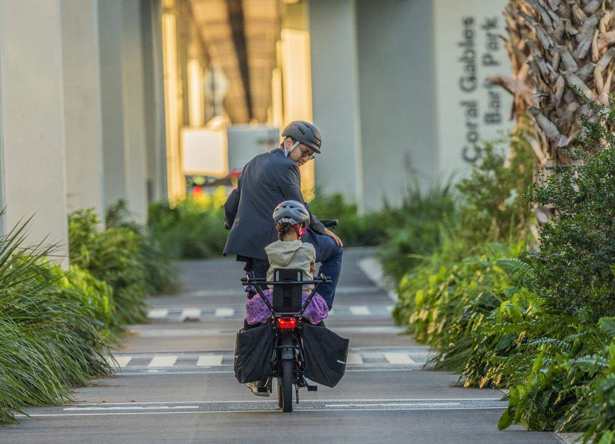 Kenneth Garcia takes his daughter to school riding his bike through The Underline in Coral Gables before heading to his work, since his family doesn't own a car, on Friday October 31, 2025.