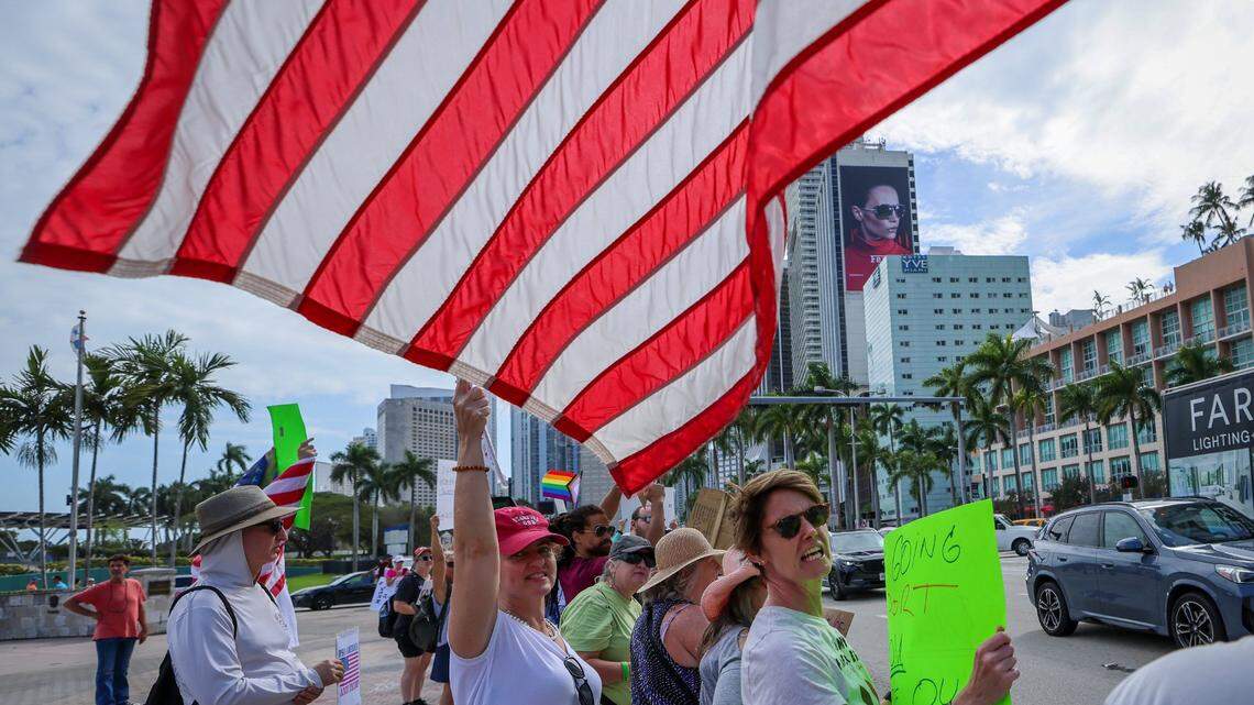 An American flag waves above the head of demonstrators during a protest against the Trump administration on Feb. 17 at the Torch of Freedom in downtown Miami.