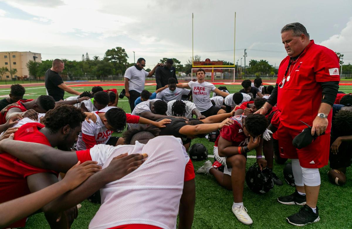 Monsignor Edward Pace football coach Mario Perez prays with his team after a preseason practice at their field in Miami Gardens, Florida on Monday, August 2, 2021.