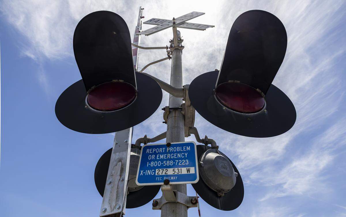 A sign tells people the number to call to report a problem at a railroad crossing near North Dixie Highway and Northeast Third Street in Pompano Beach, Florida.