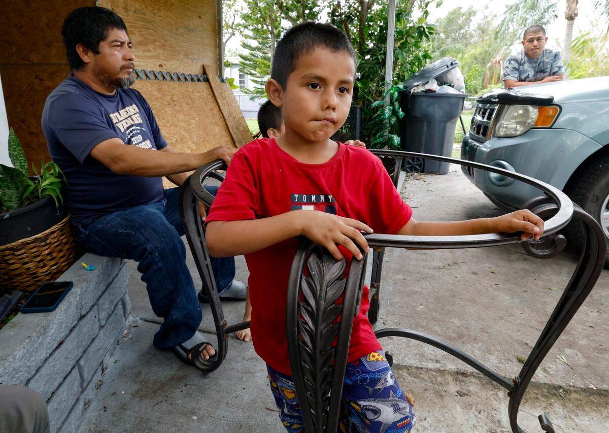 Miguel Urbina, 5, speaks about his experience evacuating his home to a shelter during Hurricane Milton as his uncle Primitivo Cesario, at left, looks towards the damage of their neighbor’s homes, at Fairmont Mobile Home Estates in Ruskin, Florida.