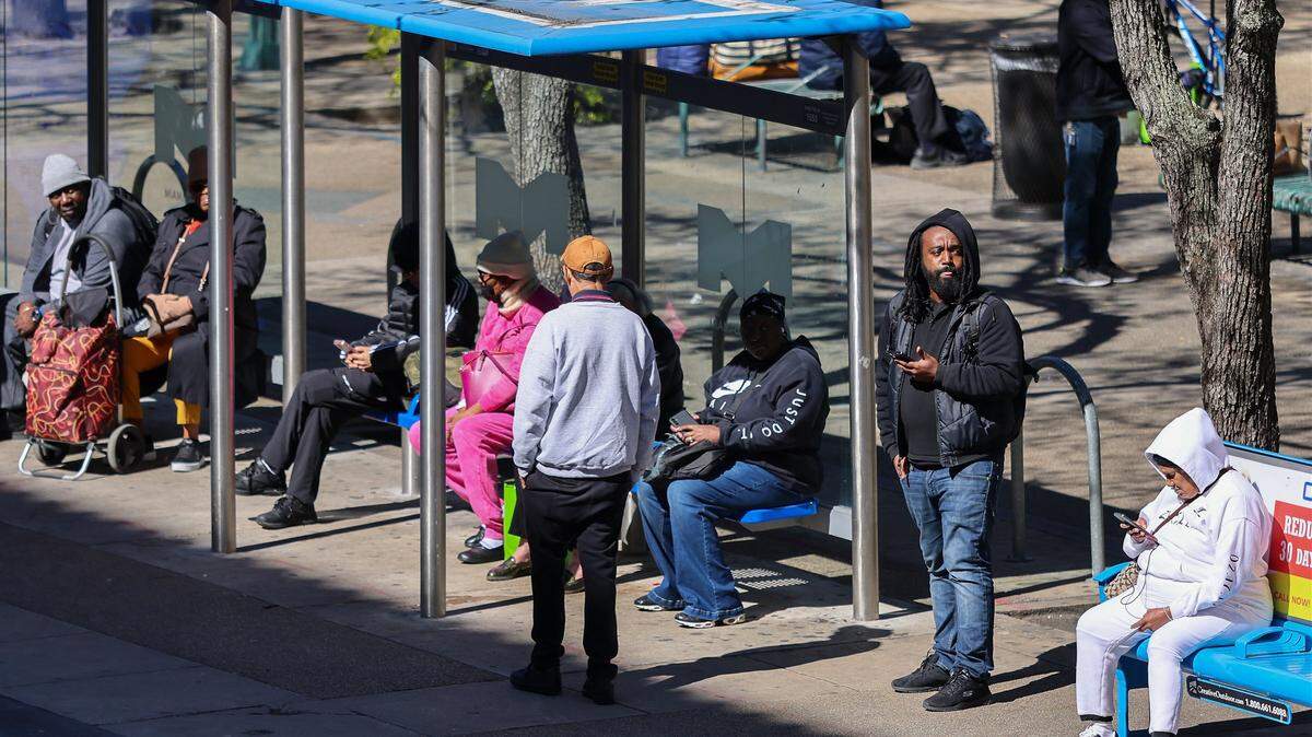 Commuters wait at the bus stop outside Miami-Dade County Hall dressed for the cold on Monday, February 2, 2026, in Miami, Florida.