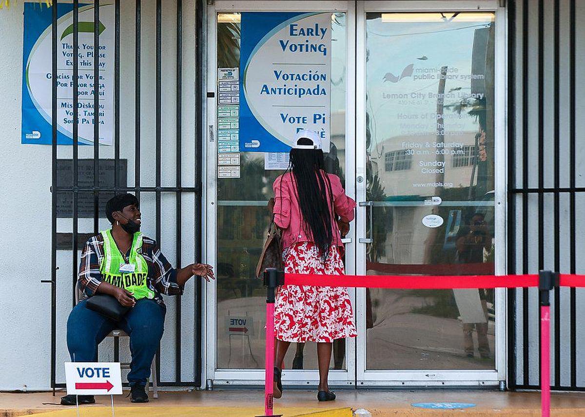 Una trabajadora electoral saluda a una electora mientras esta entra en la biblioteca para emitir su voto. El lunes 24 de octubre de 2022 los habitantes de Miami emitieron su voto durante el primer día de votación anticipada en el Condado Miami-Dade en la Lemon City Library en Miami, Florida.