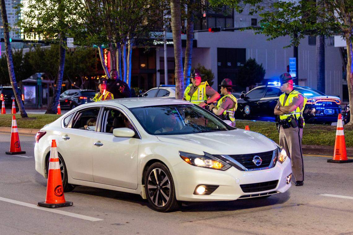 A motorist drives through a DUI checkpoint on Fifth Street between Meridian and Washington Avenues as officers from Florida Highway Patrol look on during the fourth weekend of Spring Break in Miami Beach, Florida, on Saturday, March 25, 2023. Troopers will again conduct a checkpoint on the weekends of March 8-9 and March 15-16, 2024.
