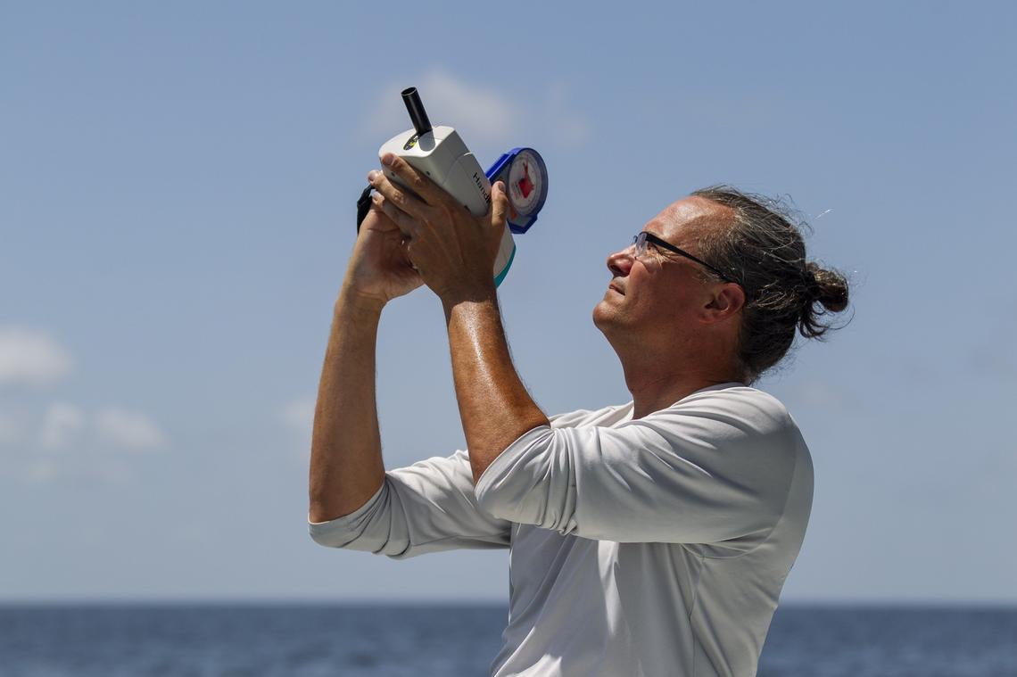 Vince Lovko, a phytoplankton ecologist, uses a spectroradiometer that measures light in water to detect the intensity of red tide off Longboat Key near Sarasota. Red tide first appeared in October and has since spread along the Southwest coast of Florida.