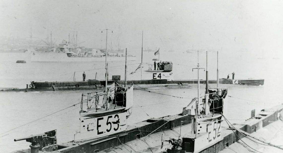 An archive photo showing the top of submarine HMS E52 in the lower right corner and several other submarines.