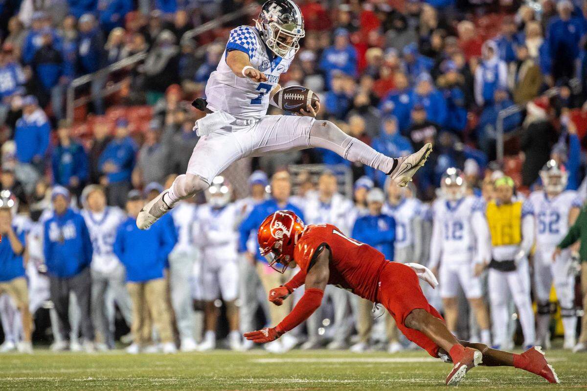 Kentucky Wildcats quarterback Will Levis (7) jumps over D*Louisville Cardinals defensive back Qwynnterrio Cole (12) during the GovernorÕs Cup at Cardinal Stadium in Louisville, Ky., on Saturday, Nov. 27, 2021.