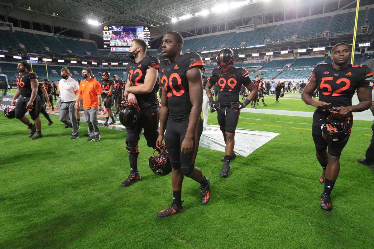 Miami Hurricanes players walk off the filed after losing to UNC at Hard Rock Stadium in Miami Gardens on Saturday, December 12, 2020.
