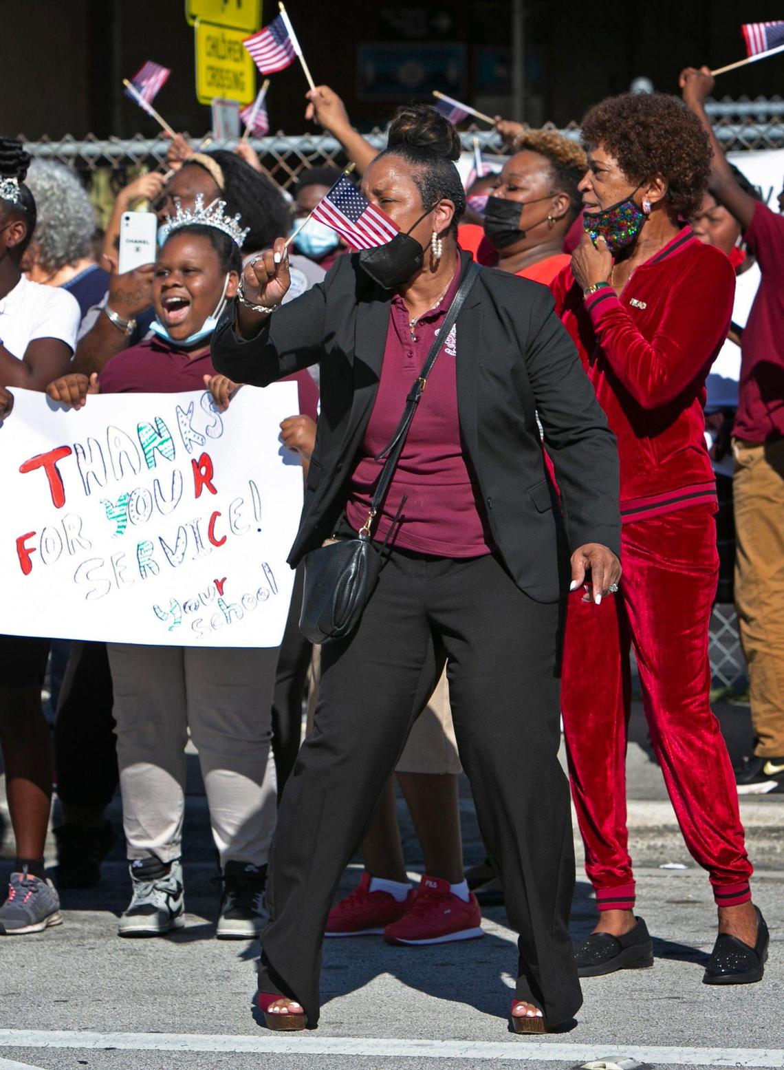 Carrie P Meek/Westview K-8 Center Principal Marchel Woods waves flags and pays respects to the late-Congresswoman Carrie Meek, along with her students. The funeral procession for Meek drove past the school Tuesday morning, Dec. 7, 2021.