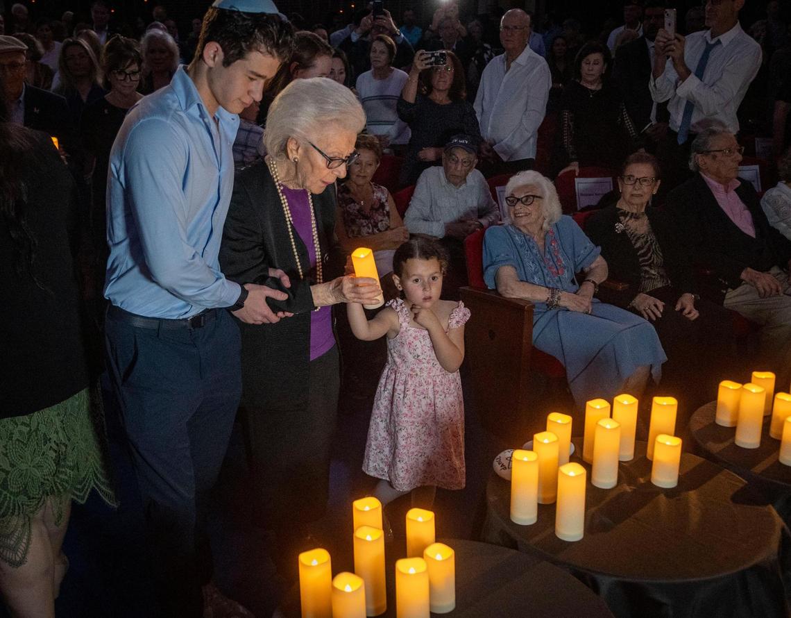 Miami Beach, FL, April 27, 2025 - Holocaust survivor, Judy Rodan, second from left, is helped along by her Grandchildren and Great-Grandchildren as she prepares to place a candle at the table during a procession of Holocaust Survivors into a ceremony to Commemorate Yom HaShoah, Holocaust Remembrance Day at Temple Emanu-El in Miami Beach.