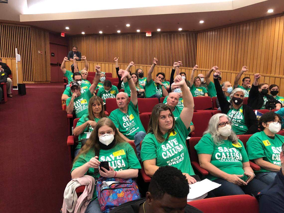 Residents opposed to a residential development on the shuttered Calusa golf course near their homes signal their disapproval during the Nov. 17, 2021 meeting of the Miami-Dade County Commission to vote on the project’s zoning approval. Save Calusa leader Amanda Prieto is in the second seat from the aisle with arm raised.
