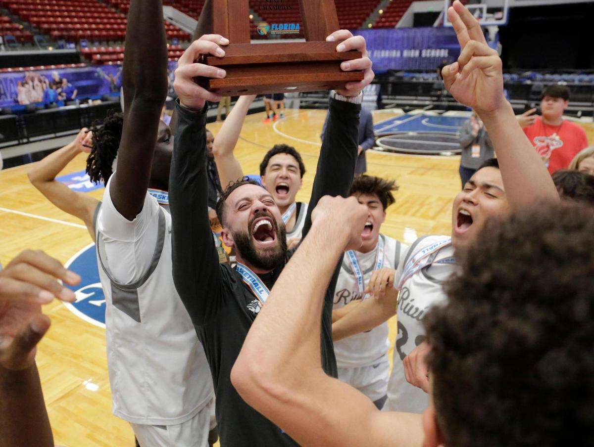 Coach Anthony Shahbaz raises the 3A State Champion trophy surrounded by his team Saturday. Riviera Prep defeated the Windermere Prep 68 to 57 to earn back to back state titles. Fhsaa 2024 State Championships Lakeland, Fl. March 1st 2024. Special to the Miami Herald / Calvin Knight.