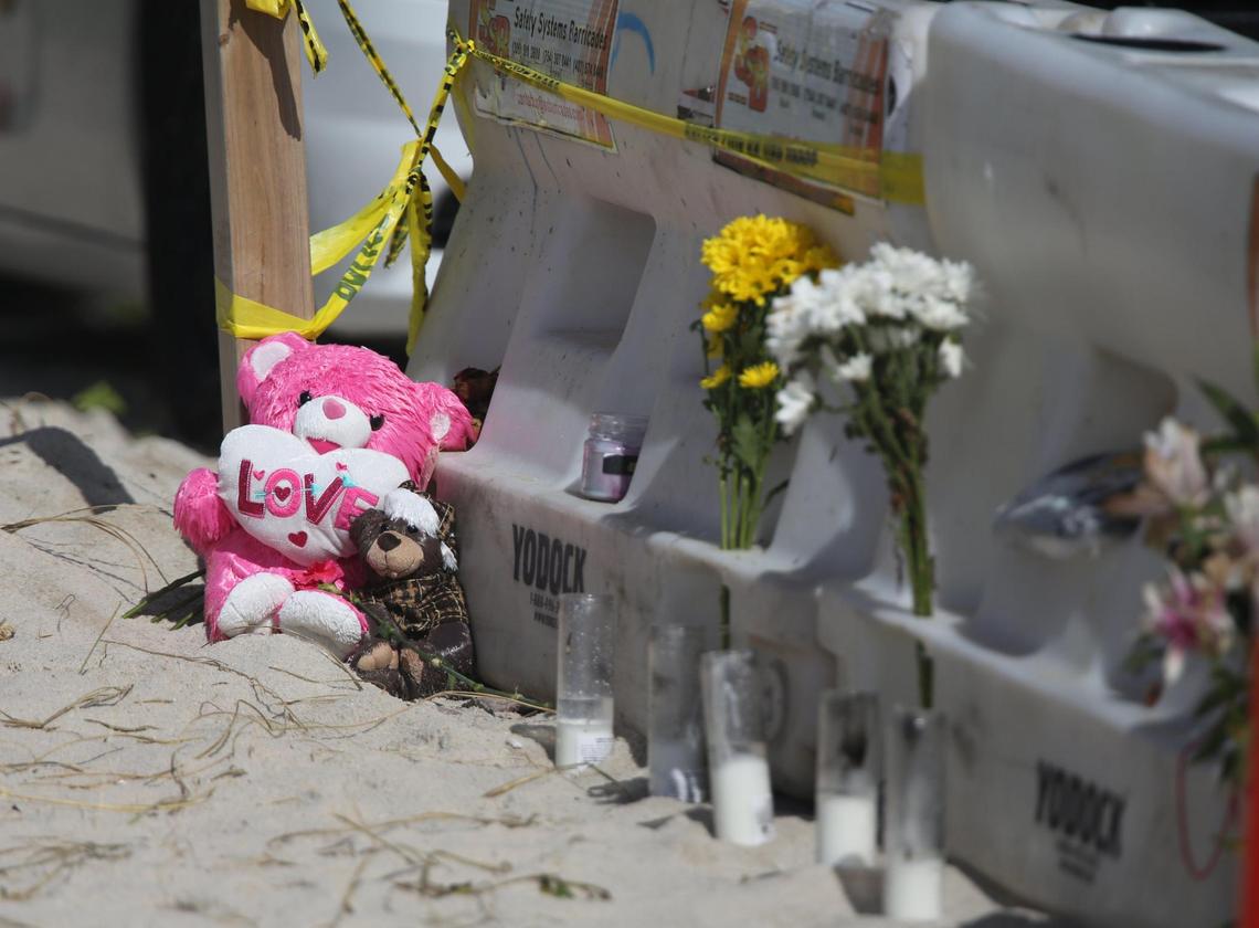 Two teddy bears sit in the sand as part of a makeshift memorial on the beach barricades just south of where workers continue their search and rescue efforts on the collapsed Champlain Towers South site Friday morning, July 2, 2021, on Day 9 of search and rescue efforts.