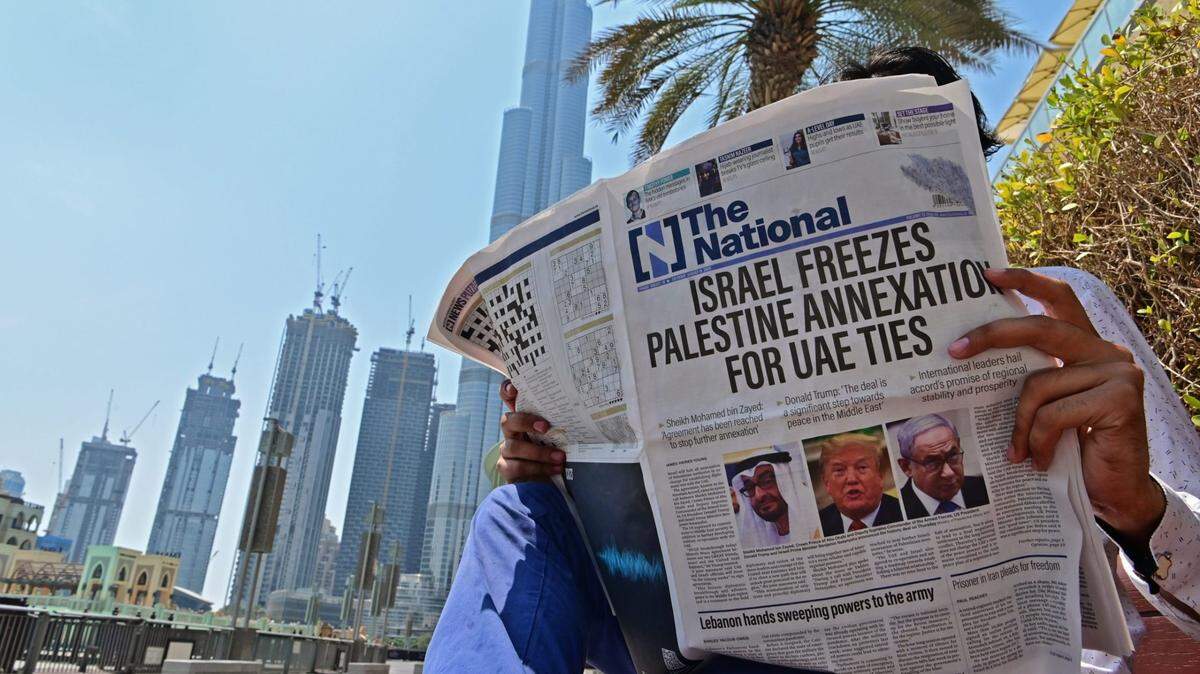 A man in Dubai reads a copy of UAE-based National newspaper, which made normalization between Israel and UAE front-page news.