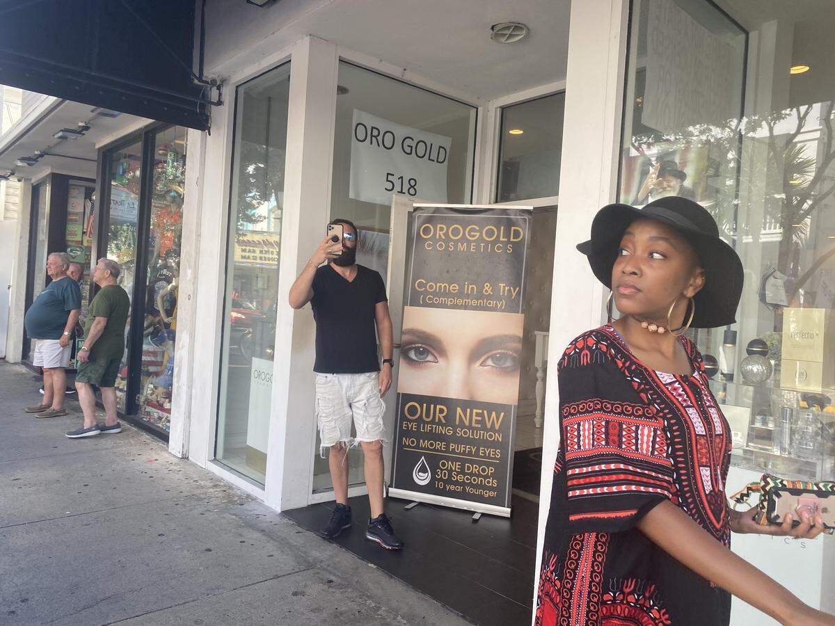Nir Chen, an owner of Orogold Cosmetics, 518 Duval St., watches as people pass by a band of protesters holding signs that call his shop a “Rip Off Shop.”