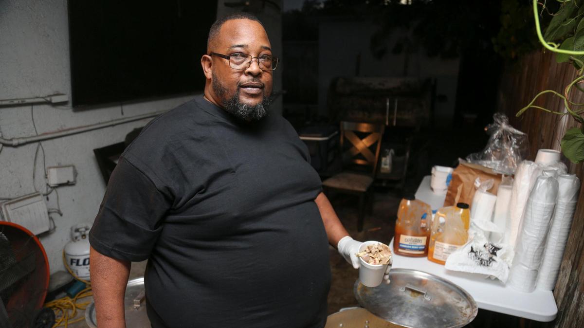 Larry D Reaves, 53, owner of World’s Famous Souseman BBQ, serves a cup of his world famous pork souse in the backyard of his Opa-locka home in Florida on Saturday, Nov. 19, 2022.