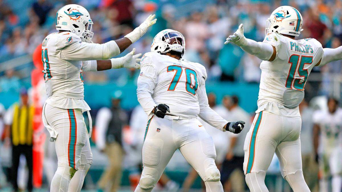 Miami Dolphins nose tackle Adam Butler (70) celebrate with teammates Emmanuel Ogbah (91) and Jaelan Phillips (15) after sacking New York Giants quarterback Mike Glennon (2) during the fourth quarter of an NFL football game at Hard Rock Stadium on Sunday, December 5, 2021 in Miami Gardens, Florida. (David Santiago Photo / Miami Herald)