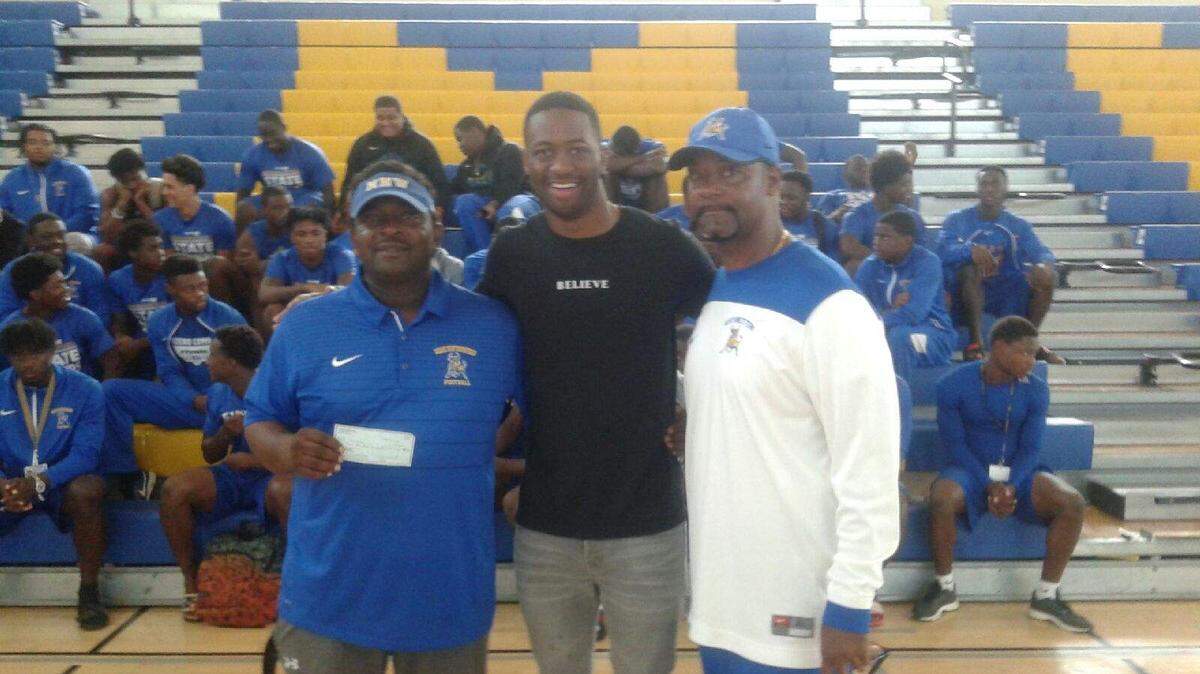 With their Northwestern Bulls football team looking on, head coach Max Edwards (left) and athletic director Andre Williams (right) were on hand on Saturday morning to accept a check from VICIS representative Jared Green, son of NFL Hall of Famer Darrell Green.