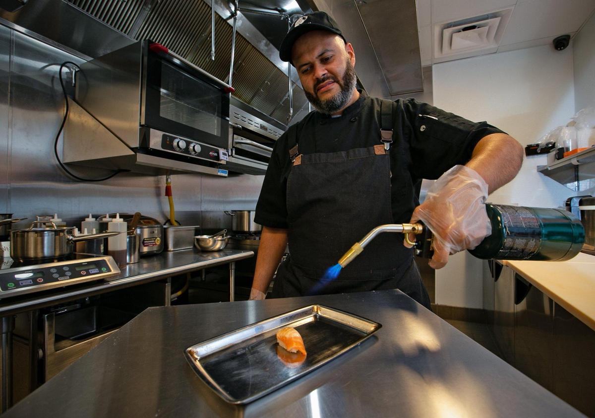 Chef Francisco Bartillo prepares a torched salmon nigiri at the recently opened Belly Fish sushi restaurant in the CORE Link apartments at the Douglas Road Metrorail Station, the hub of a bustling new urban neighborhood.