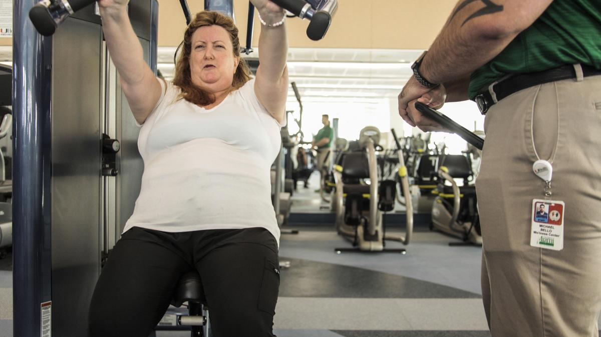 Dr. Elizabeth Crucco does some weightlifting while Michael Bello, a UHealth health and fitness specialist, checks her posture and monitors her heart rate. When she turned 50 last year, she made a life-changing decision to get in shape.
