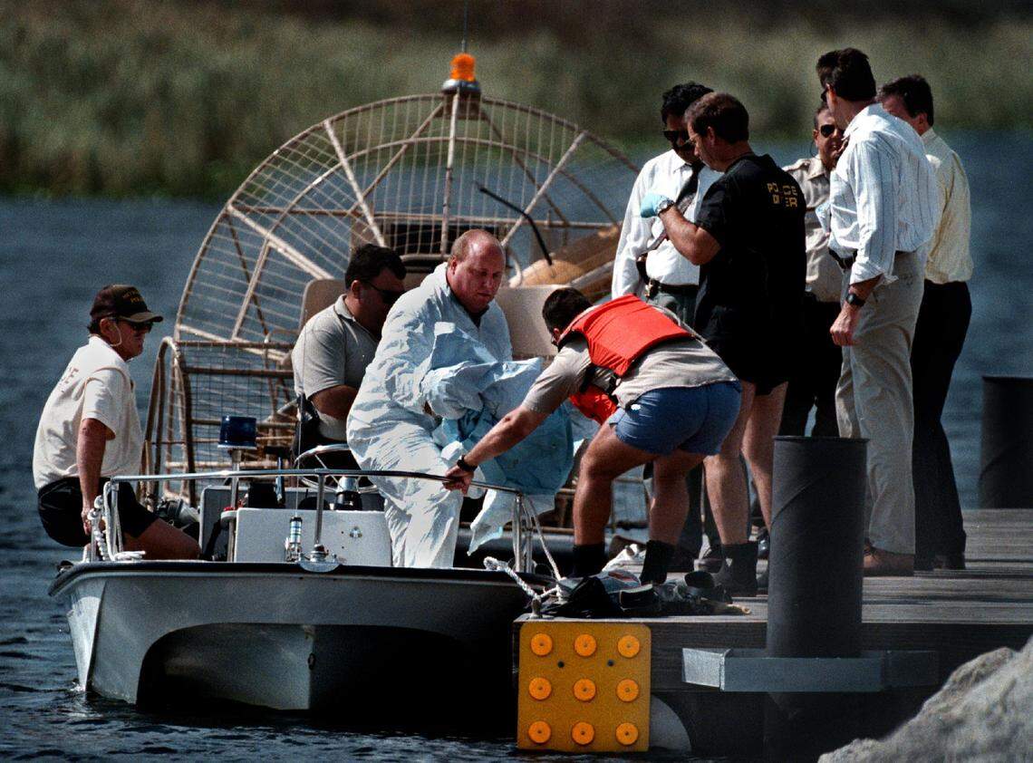 An employee of the Broward County Medical Examiner (in white suit) lifts the body of Quatisha Maycock and brings it ashore the boat dock off Alligator Alley. The body was found by two fishermen on Nov. 9, 1998.