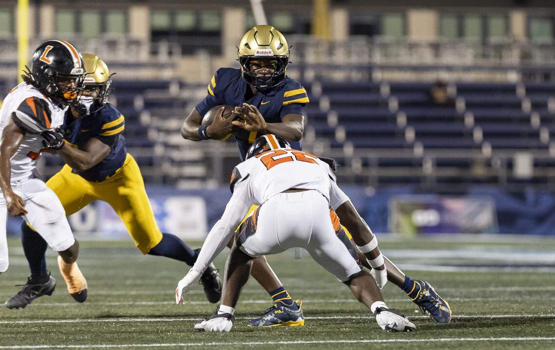 St. Thomas Aquinas Raiders quarterback Mason Mallory (7) runs with the ball as Lakeland Dreadnaughts defensive back Deonte Fielder (22) goes for a tackle in the first half of their Class 5A state championship football game at Pitbull Stadium on Thursday, Dec. 11, 2025, in Miami, Fla.