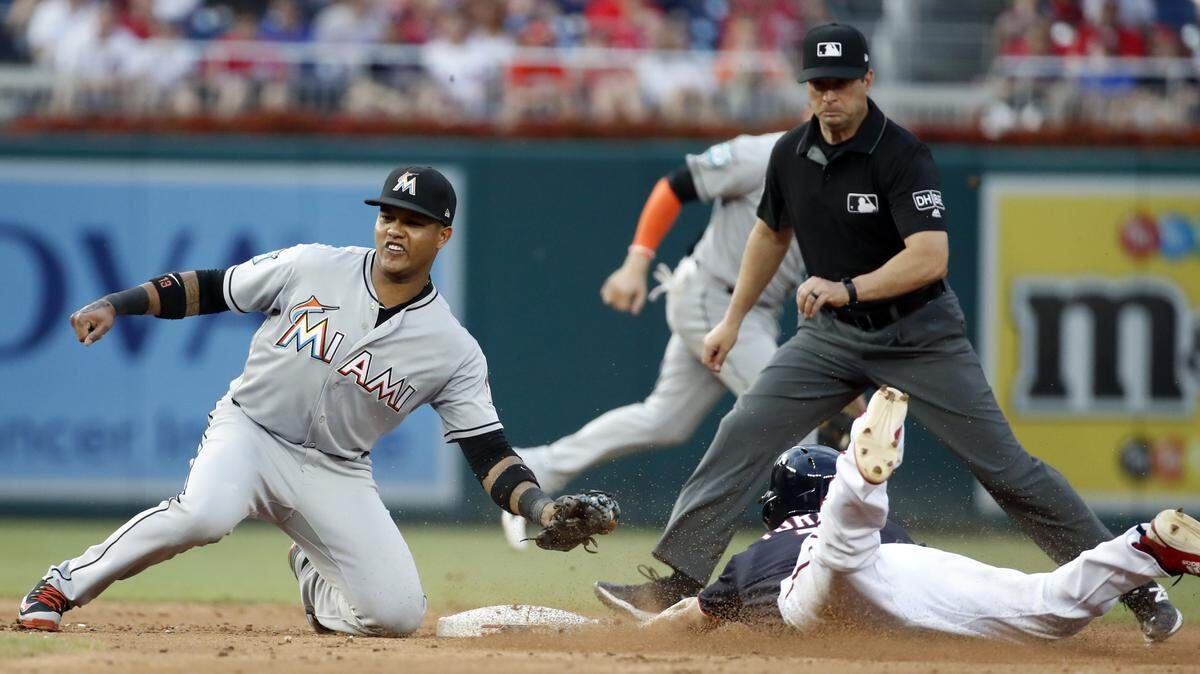 Miami Marlins second baseman Starlin Castro, left, at first cannot tag Washington Nationals' Trea Turner, bottom right, on a steal-attempt of second base with second base umpire Jim Reynolds, top right, during the third inning of a baseball game at Nationals Park, Friday, July 6, 2018, in Washington. Turner slid past the base andwas out on play. (AP Photo/Alex Brandon)