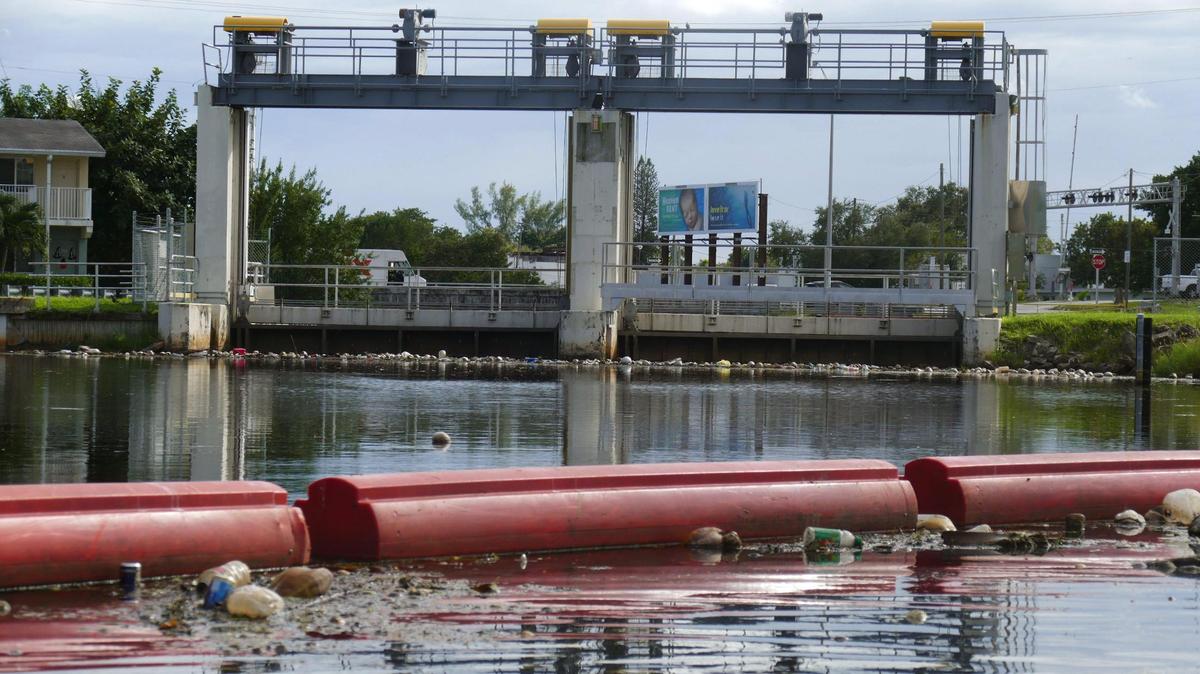 An orange, floating berm used to collect garbage and debris stretches across the Little River just north of the South Florida Water Management District’s flood control device near NE 82nd St and NE fourth Pl. Friday October 15, 2021. The berm also marks the end point for any water vessels heading east along the Little River. To continue along the river past this point boats would have to be lifted out of the water and carried across NE 82nd St.
