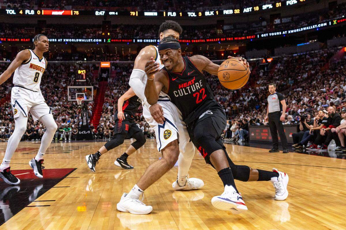 Miami Heat forward Jimmy Butler (22) drives toward the basket on Denver Nuggets guard Jamal Murray (27) during the second half of an NBA game at Kaseya Center in Miami, Florida, on Wednesday, March 13, 2024.