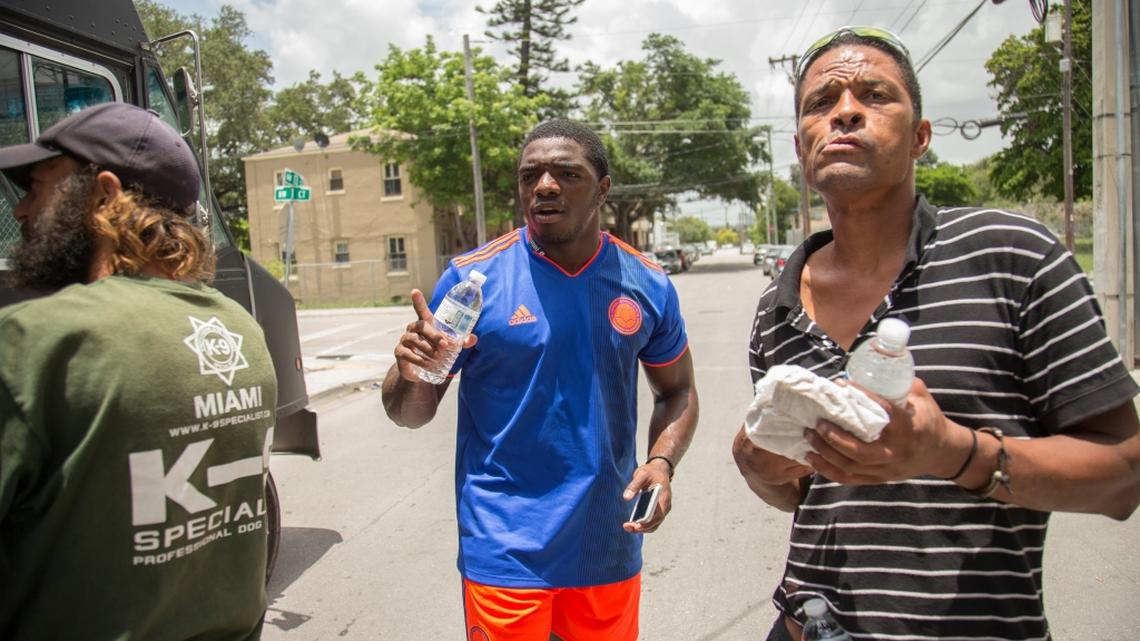 University of Miami football player Robert Burns  gives out food and water in the neighborhood of Overtown in Miami on Saturday, July 7, 2018.