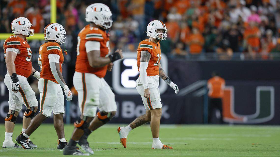 Miami Hurricanes quarterback Carson Beck (11) walks off the field with teammates after getting picked off by Louisville Cardinals linebacker T.J.Capers (11) on a pass intended for Miami Hurricanes tight end Elija Lofton (9) late in the fourth quarter of their NCAA football game at Hard Rock Stadium in Miami Gardens, Florida, on Friday, October 17, 2025.