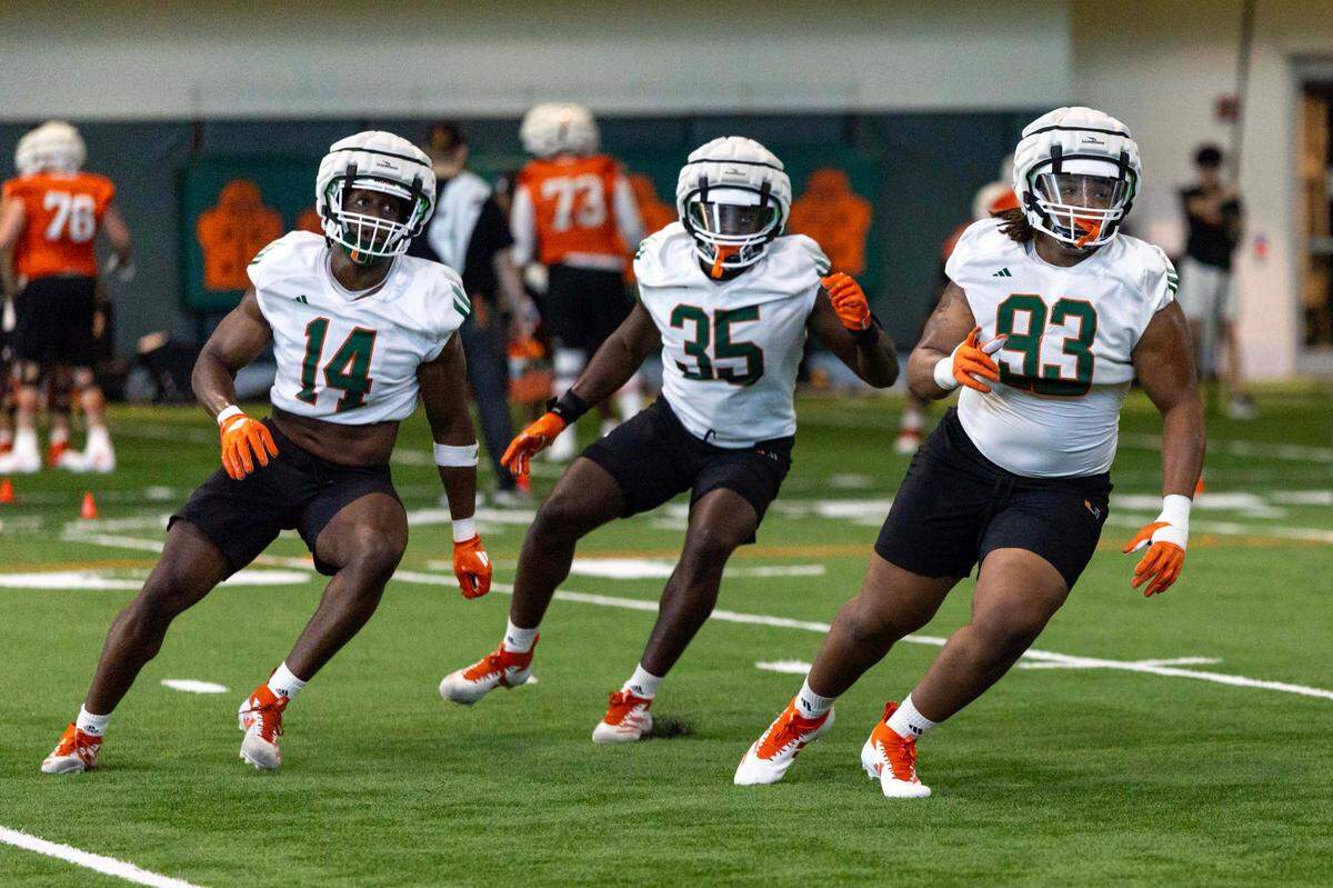 Miami Hurricanes defensive linemen Hayden Lowe (14), Herbert Scroggins III (35) and Donta Simpson, Jr. (93) run through drills during spring practice at the Carol Soffer Indoor Practice Facility at the University of Miami on Wednesday, March 5, 2025, in Coral Gables, Florida.