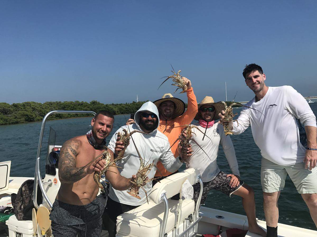 Ray Ruiz, Nick Avila, Anthony Goodhue, Sebastina and Corey Weech, all from Fort Lauderdale, stand on a boat in Snake Creek holding spiny lobsters they caught Wednesday, July 24, 2019, in Islamorda.