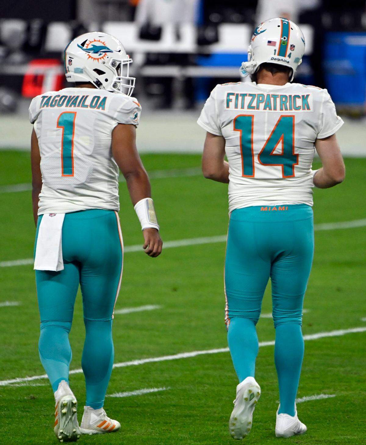 Miami Dolphins quarterbacks Tua Tagovailoa (1) and quarterback Ryan Fitzpatrick (14) walk together during warm ups before an NFL football game against the Las Vegas Raiders, Sunday, Dec. 26, 2020, in Las Vegas.
