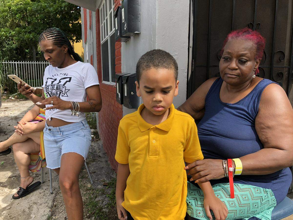 Mary Davis, right, looks at her 5-year-old grandson, Cesar, while April Monroe looks on her phone for videos of the worst sewage backups.