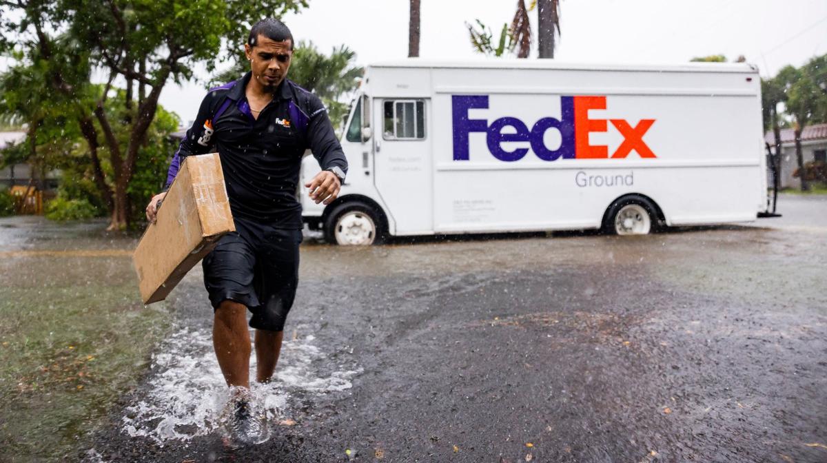 FedEx driver Rico Torres, 33, delivers a package to a home near Hayes Street as heavy rain flooded the neighborhood on Wednesday, June 12, 2024, in Hollywood, Fla.