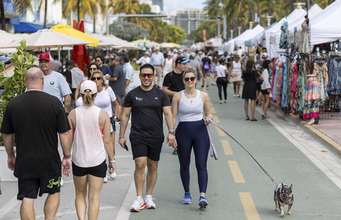 Gerry Tenebruso, Isabella Livia and her small dog, Gigi, make their way down Ocean Drive during Art Deco Weekend on Saturday, Jan. 10, 2026, in Miami Beach, Fla.