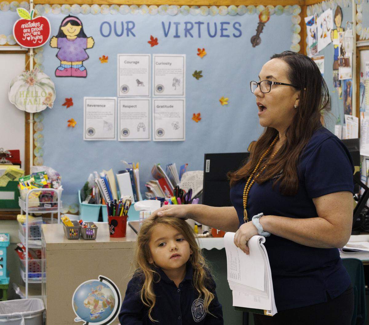 Ms. Geraldine Cameron pats a child on the head during the school day on Tuesday, Nov. 18, 2025, at Village Green Elementary School in Miami, Fla. Cameron has helped to implement a classical education system at the school that originates from Ancient Greece meant to cultivate critical thinking and virtues in its students, and it disconnects them from technology to focus on active listening.