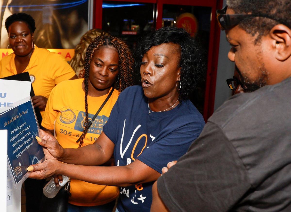 NAACP member Ebony Johnson, at center, asks K Miller, at right, contest questions during an effort to register hard-to-reach voters at Tootsie’s Cabaret in Miami Gardens on Friday, October 4, 2024.