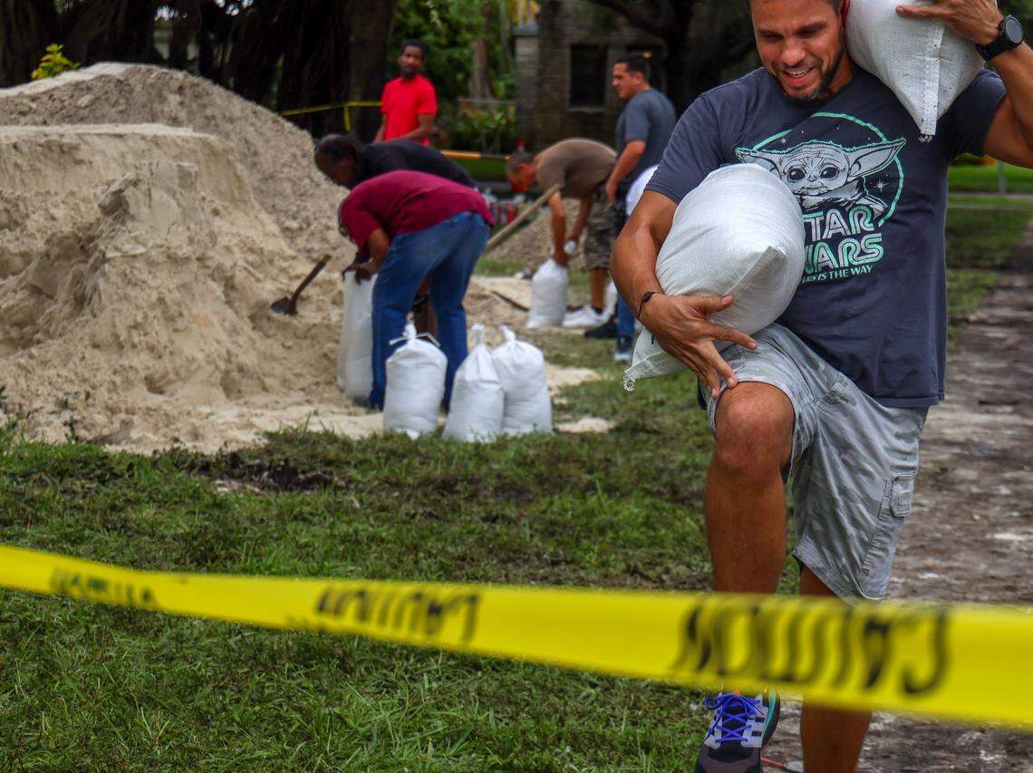 Emanuel Atencio tries to position sandbags on his shoulder as Hollywood residents join South Floridians in preparation for possible flooding due to Hurricane Milton in Broward and Miami-Dade counties at Jefferson Park in Hollywood, Florida, on October 8, 2024.